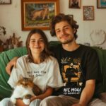 Para z kotem w T-shirt Nie Mogę Kot Na mnie Leży – merch dla kociarzy, bawełniany z relaksującą ilustracją mężczyzny z pupilem, na wspólne leniwe chwile.